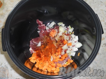 Свинину, лук и морковь выложить в чашу мультиварки, влить растительное масло. Посолить, посыпать специями, добавить два вида паприки и красный молотый перец.