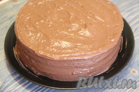Собрать шоколадный медовик "Дамский каприз", смазывая коржи тёплым заварным шоколадным кремом и выкладывая их друг на друга. Верх и бока торта хорошо обмазать кремом.