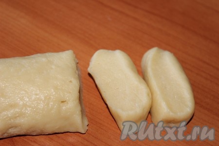 Сначала тесто перемешивать ложкой, а как только тесто начнет собираться в ком, начать замешивать тесто руками. По консистенции должно получиться гладкое и однородное тесто. Затем тесто раскатать в овал примерно 4 сантиметра в диаметре. Полученный овал разрезать на небольшие кусочки.
