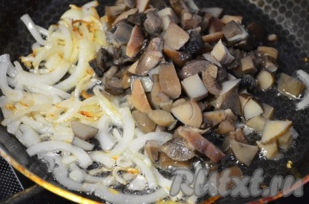 Отваренные замороженные грибы разморозить (свежие лесные грибы нужно предварительно перебрать, вымыть и сварить в течение 40 минут до готовности), нарезать помельче. Лук нарезать полукольцами или кубиками (как вам нравится). Обжарить лук на растительном масле, помешивая, до золотистого цвета, затем добавить грибы и готовить, не забывая помешивать, ещё 3 минуты.
