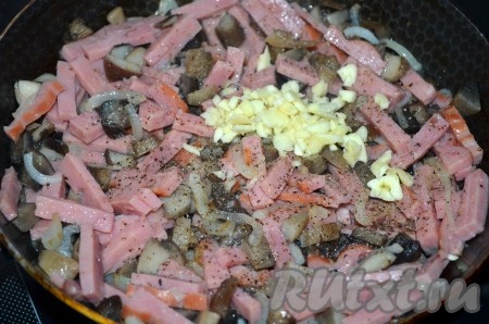 Добавить к луку и грибам измельченный чеснок и ветчину, перемешать, обжаривать ещё 3-5 минут, помешивая.