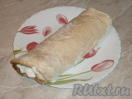 Свернуть меренговый корж, смазанный творожным кремом, начиная с широкой стороны с помощью пергамента, в рулет.