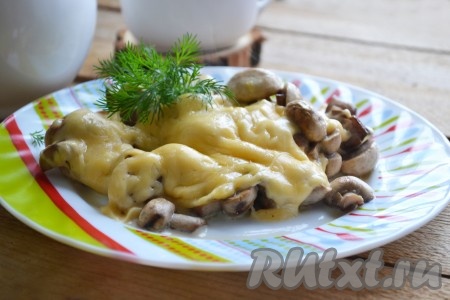 Шампиньоны, запеченные под сыром в духовке, готовы, можно подавать на стол, украсив веточкой зелени.

