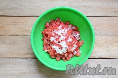 Нарезаем помидоры на мелкие кубики и выкладываем в миску. К чесноку, пропущенному через пресс, добавляем соль и перемешиваем. Чесночную смесь выкладываем в помидоры и ещё раз перемешиваем.