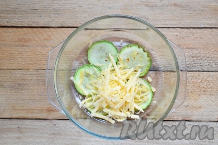 Сыр натираем на крупной тёрке. Форму для запекания, по желанию, смазываем маслом (я не смазывала). Выкладываем часть кабачков в один слой в форму для запекания, посыпаем частью натёртого сыра.