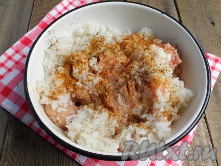 К фаршу добавить пропущенный через мясорубку или натертый на терке репчатый лук. Рис отварить до готовности и остудить, добавить в фарш, посолить, поперчить, посыпать специями. Тщательно фарш перемешать.
