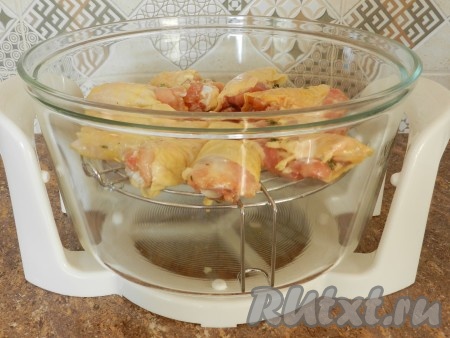 Затем выложить кусочки курицы на верхнюю решетку аэрогриля, травы можно завернуть внутрь или под кожицу.