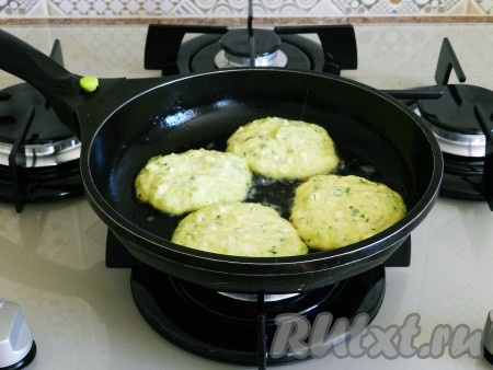 В сковороде разогреть растительное масло. В разогретое масло выкладывать по 1-1,5 столовых ложки кабачково-творожного теста, жарить оладьи до подрумянивания снизу на среднем огне.