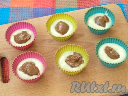 В силиконовые формочки выложить немного теста, на него - по чайной ложечке варёной сгущёнки.
