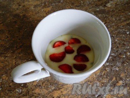 Тесто переложить в чашку (или другую посуду), пригодную для микроволновки, заполняя не более, чем на половину объёма. Добавить кусочки клубники, вдавив их в тесто. Чашку поставить в микроволновку, выпекать кекс 1,5-2 минуты при мощности 800 Вт.