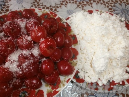 Для приготовления начинки для вареников в отдельных тарелках смешиваем вишню с 3 столовыми ложками сахара, а творог перемешиваем с 2 столовыми ложками сахара.