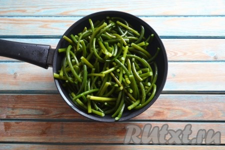 Подготовленные стрелки чеснока солим по вкусу. Сковороду хорошо разогреваем с растительным маслом. Выкладываем стрелки чеснока на сковороду.