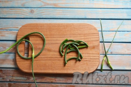 Стрелки хорошо промываем проточной водой. У каждой стрелки чеснока срезаем соцветие (оно нам не понадобится). Нарезаем стрелки на равные кусочки длиной примерно 5-6 сантиметров. Желательно, чтобы на стрелках не было воды, можно их даже обсушить на бумажных полотенцах.