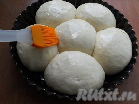 Накрыть форму пищевой пленкой и оставить тесто в теплом месте для подхода на 1 час. Смазать подошедшие колобки сверху растительным маслом.