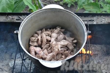 Плов будем готовить на мангале. В горячий котелок выкладываем нарезанное мясо и периодически помешиваем.
