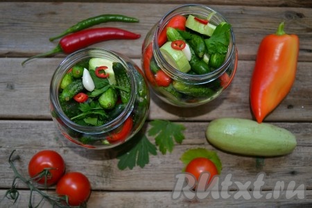 С болгарского перца срезать плодоножки и удалить семена, нарезать на кубики. Молодой кабачок (кожуру можно не снимать) нарезать на дольки или кружочки. Уложить достаточно плотно наше ассорти, чередуя овощи. Маленькие огурчики и помидоры не режем, а добавляем целиком. Острый перец добавить по вкусу, если не любите острое, то просто не кладите его в ассорти (если любите поострее, добавьте целый острый перчик). В каждую банку уложить сверху несколько очищенных зубчиков чеснока.
