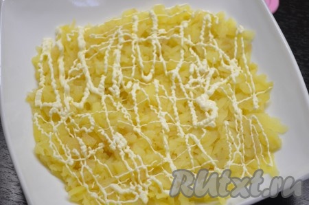 Салат "Гренадер" готовится слоями. Первый слой - вареная картошка, натертая на терке. Смазать сеточкой майонеза, посолить.