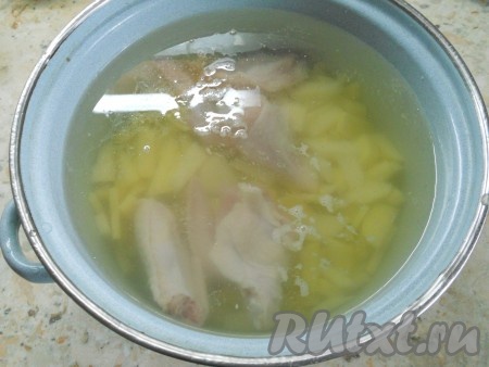 Куриные крылышки вымыть, поместить в кастрюлю и залить 3 литрами воды. Поставить кастрюлю на огонь, довести до кипения, убрать пену. Бульон посолить и варить крылышки 15-20 минут. Если используете домашнюю курицу или свинину, говядину - время варки нужно увеличить до 40-45 минут. Далее добавить в кастрюлю нарезанный кусочками картофель. Варить на небольшом огне до готовности картошки (20-25 минут).
