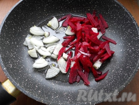 Лук репчатый нарезать кусочками, свеклу - тонкими брусочками. Поместить овощи в сковороду с растительным маслом и обжарить в течение 8-10 минут на среднем огне.
