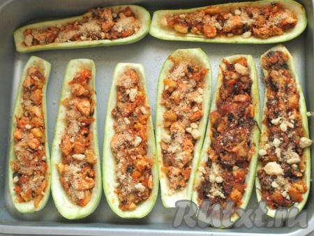 Лодочки из кабачков разместить в подходящей по размеру форме для запекания (или выложить на противень). Полученной смесью из куриного филе и овощей наполнить лодочки из кабачков. Сверху можно дополнительно посыпать измельчёнными сухариками.