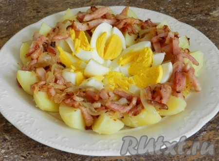 На картошку выложить обжаренную грудинку с луком.
