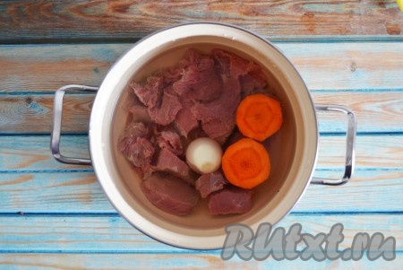 Выкладываем кусочки говядины в кастрюлю, заливаем водой и добавляем очищенный лук и половинку моркови. Ставим на огонь. После закипания, снижаем к минимуму огонь и периодически снимаем пену. Варим, приблизительно, час.
