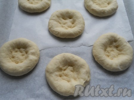 Тесто обмять и разделить его на 6 равных частей. Каждую часть скатать в шарик и приплюснуть. Поместить лепешки на противень, застеленный пергаментом (пергамент лучше посыпать мукой). Пальцами или дном стакана сделать в лепешках углубления.