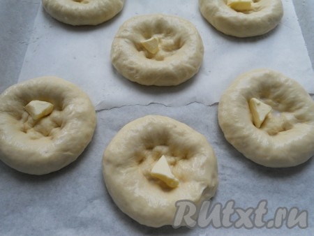 Для смазывания ватрушек теплое молоко смешать с небольшим количеством сахара. Этой смесью смазать все лепешки. В углубление каждой лепешки поместить по небольшому кусочку сливочного масла.
