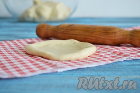 На присыпанной мукой поверхности немного раскатываем скалкой каждый кусочек теста в лепёшку.