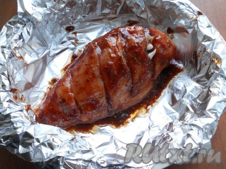 В надрезы на куриной грудке поместить нарезанный небольшими кусочками или пластинами чеснок. Контейнер для варки на пару застелить листом фольги, поместить туда куриную грудку. Сверху щедро смазать мясо подготовленным соусом.
