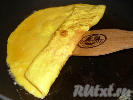 Затем с помощью лопатки, начиная с одного края, свернуть омлет рулетом. 