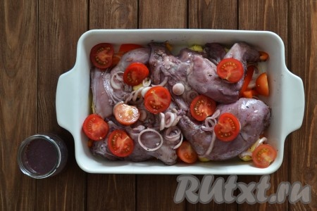 Сверху выкладываем подготовленные кусочки кролика и лук, который мариновался в красном вине вместе с мясом. Помидоры разрезаем на две части (если вы используете крупные помидоры, их нужно разрезать на 3-4 части) и выкладываем в форму.
