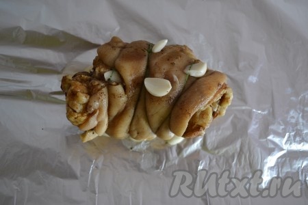 Выкладываем рулет из свиной рульки на фольгу вместе с очищенными зубчиками чеснока.
