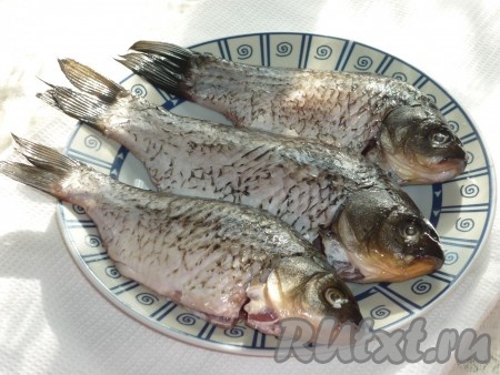 Карасей очистить от чешуи и внутренностей. Удалить жабры и срезать кухонным ножом плавники. Хорошо промыть под холодной проточной водой несколько раз, так как рыба речная. Обсушить бумажным полотенцем. Натереть карасей солью, перцем и приправой внутри и снаружи, сбрызнуть лимонным соком и оставить на 10-15 минут. 