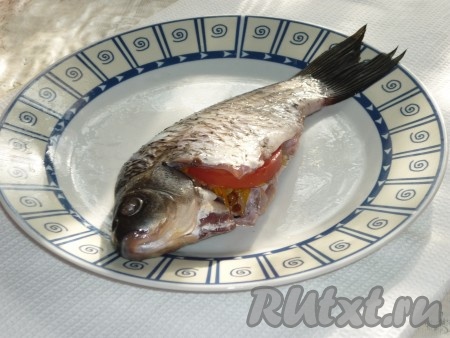 Помидор вымыть и нарезать полукольцами, положить в брюшки рыб по несколько кусочков.&nbsp;
