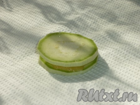 Сыр нарезать тонкими пластинками и положить по одной пластинке между двумя кружочками кабачка. 