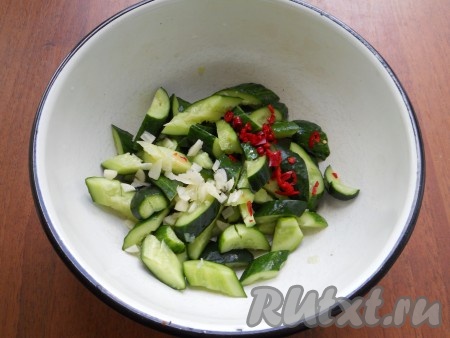 Выделившуюся жидкость с огурцов слить, добавить к ним измельченный чеснок и мелко нарезанный перец чили.
