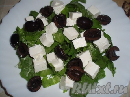 Маслины нарезать кусочками и выложить поверх сыра и листьев салата.
