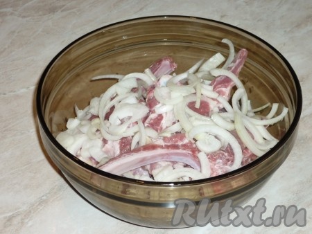 Лук нарезать полукольцами и немного помять его руками, чтобы пустил сок. Добавить лук к рёбрышкам.&nbsp;
