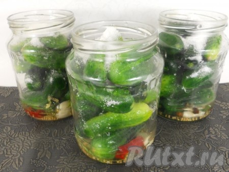Огурчики хорошенько вымыть и наполнить ими банки. Сверху всыпать соль и сахар.