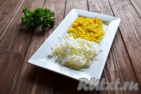Яйца, сваренные вкрутую, очищаем и разделяем на белки и желтки. На мелкой терке по отдельности натираем белок и желток.
