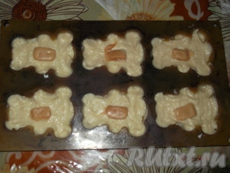 Берем наши формочки для кексов и наполняем их до середины тестом, выкладываем конфетки.
