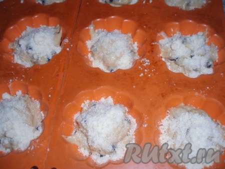 Приготовленное тесто выложить в силиконовые формочки для кексов, заполняя их на 2/3 объёма. Если будете использовать железные формочки, то обязательно смажьте их маслом. По желанию, будущие кексы с черникой перед выпечкой можно посыпать штрейзелем. Для приготовления штрейзеля нужно смешать муку, сахар и растопленное сливочное масло до образования крошки и посыпать тесто для кексов, выложенное в формочки.