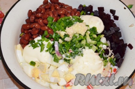 Чеснок очистить. Зелёный лук вымыть. С консервированной фасоли слить жидкость. В миску с яйцами и крабовыми палочками добавить свеклу, фасоль, мелко нарезанный лук, пропущенный через пресс чеснок, соль, чёрный молотый перец и майонез, хорошо перемешать салат.