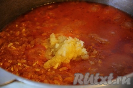 Через указанное время добавить в аджику уксус и выдавленный чеснок, хорошо перемешать и варить еще 10 минут.
