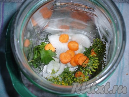 Банки стерилизовать привычным способом. Простерилизованные банки вынуть и поставить на полотенце. На дно каждой баночки поместить зелень укропа и петрушки, кружочки лука и моркови, зубчики чеснока.