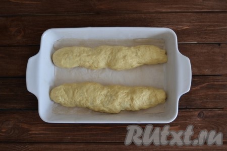 Вымешиваем еще раз хорошенько тесто. Далее тесту можно придать любую форму, я решила выпечь в виде батонов. Тесто делим на две части. Из каждой части скатываем валик, стараемся, чтобы колбасы сверху не было, прячем ее под тесто. Выкладываем батоны в форму для выпекания, смазанную маслом, или застеленную пекарской бумагой. Накрываем салфеткой и ждем 30 минут, пока хлеб, замешанный на кефире и дрожжах, подойдёт. Смазываем тесто слегка взбитым белком и посыпаем кунжутом.