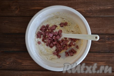 Добавляем нарезанную колбасу в миску с тестом, перемешиваем.
