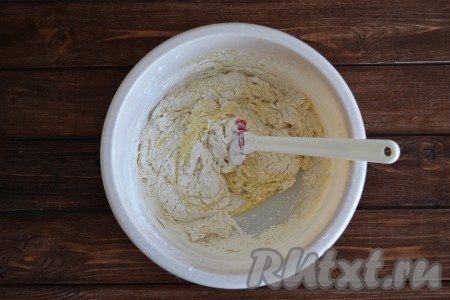 Всыпаем половину просеянной муки. И тщательно перемешиваем тесто.
