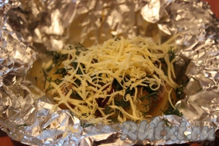 Горячий картофель аккуратно развернуть и сразу же посыпать мелко рубленной зеленью и натертым на мелкой терке сыром.